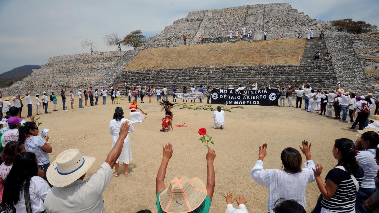 Des gens sont en rond, les bras en l'air, devant une pyramide. Des gens sont en rond, les bras en l'air, devant une pyramide.