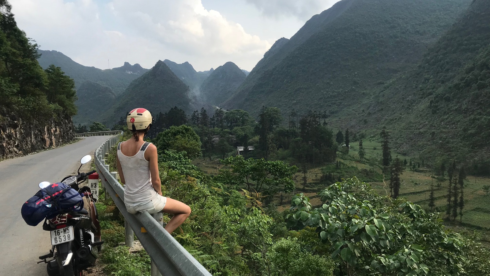 Une femme assise en bordure d'une route regarde un paysage. Une femme assise en bordure d'une route regarde un paysage.