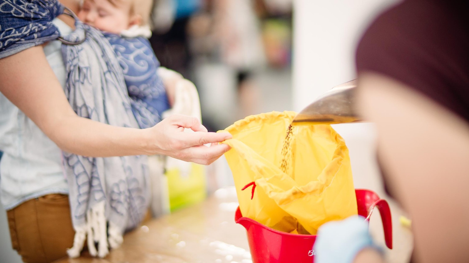 Une femme avec un bébé dans les mains tient un sac pendant qu'il se fait remplir de grains. Une femme avec un bébé dans les mains tient un sac pendant qu'il se fait remplir de grains.