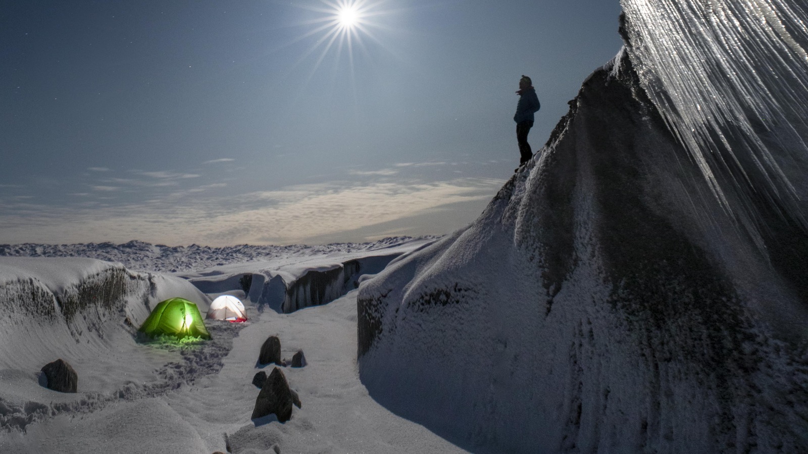 Un homme se tient sur une colline enneigée, en regardant un paysage glacé Un homme se tient sur une colline enneigée, en regardant un paysage glacé