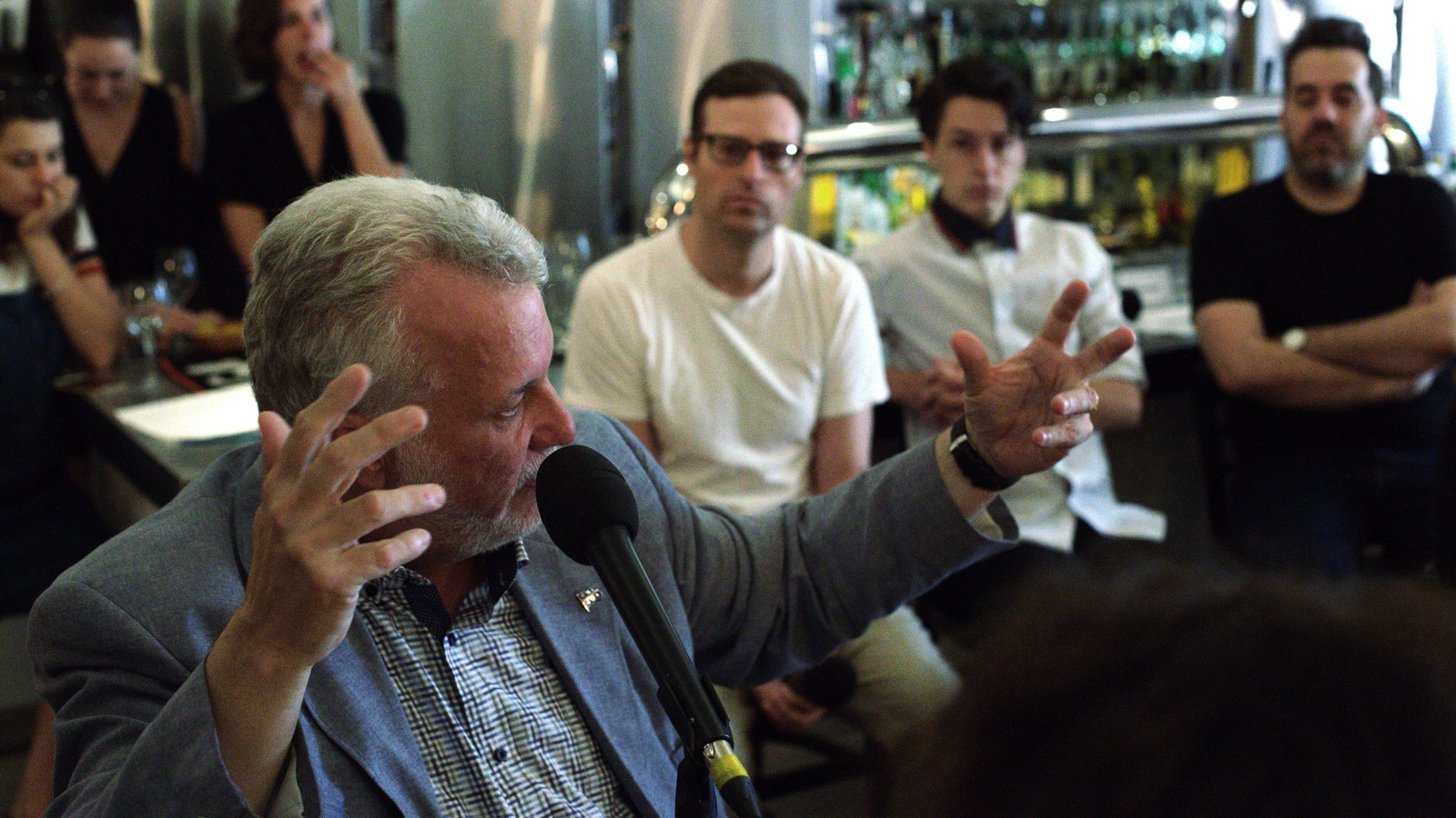 Philippe Couillard lève les bras en se retournant vers les autres invités de l'émission. Philippe Couillard lève les bras en se retournant vers les autres invités de l'émission.