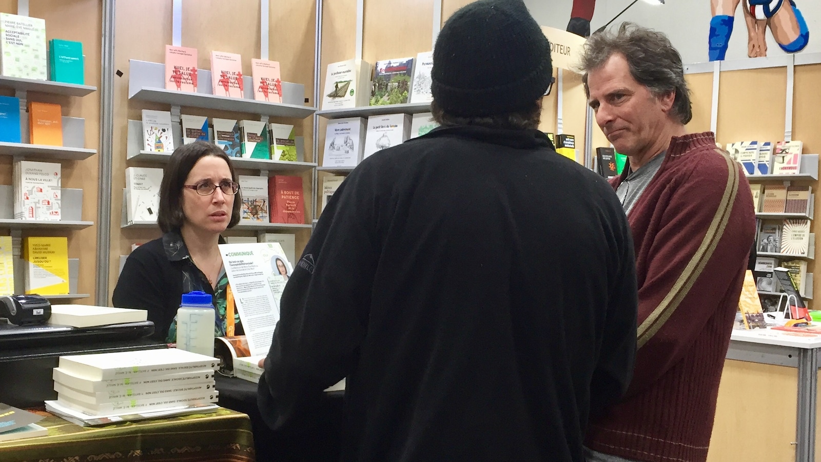 L'auteure Marie-Ève Maillé au Salon du livre de la Côte-Nord, discutant d'acceptabilité sociale avec le public, devant son kiosque de livres L'auteure Marie-Ève Maillé au Salon du livre de la Côte-Nord, discutant d'acceptabilité sociale avec le public, devant son kiosque de livres