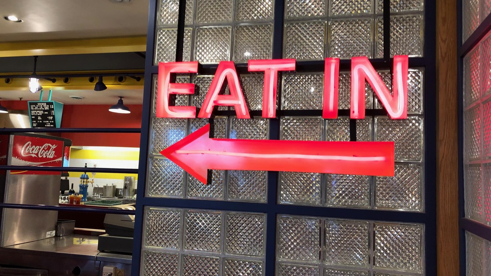 Une affiche en néon avec l'indication «Eat In» avec une flèche qui pointe vers la gauche. Une affiche en néon avec l'indication «Eat In» avec une flèche qui pointe vers la gauche.