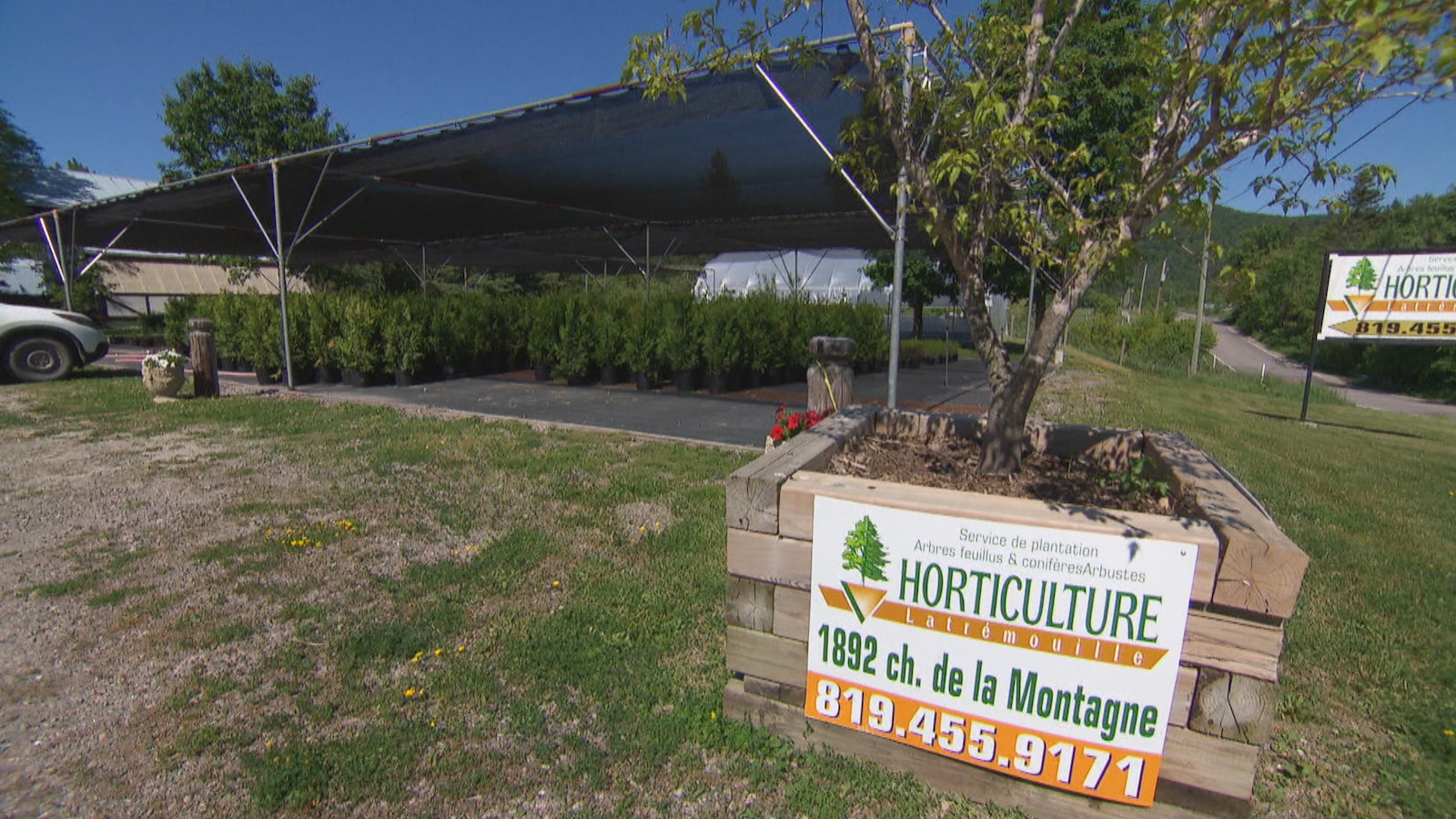 Une affiche annonçant un centre d'horticulture devant des arbres. Une affiche annonçant un centre d'horticulture devant des arbres.