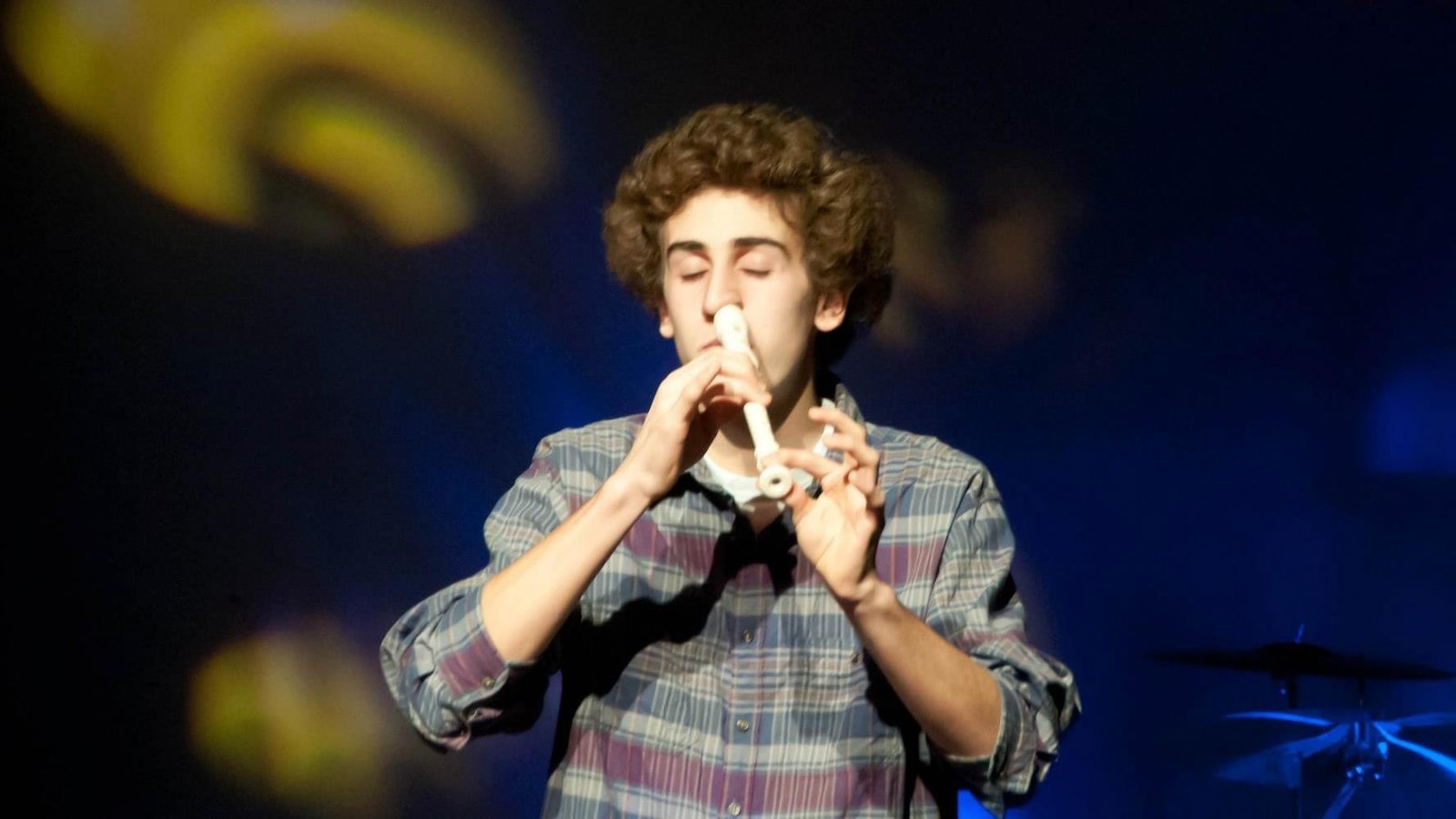 Le jeune homme joue de la flute avec son nez et ferme les yeux.
