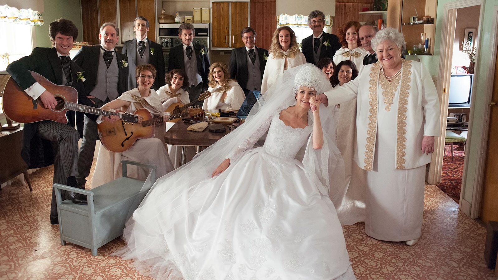 Une femme en tenue de mariée (Valérie Lemercier) entourée de toute une famille habillée en blanc, et tenant des guitares. Une femme en tenue de mariée (Valérie Lemercier) entourée de toute une famille habillée en blanc, et tenant des guitares.