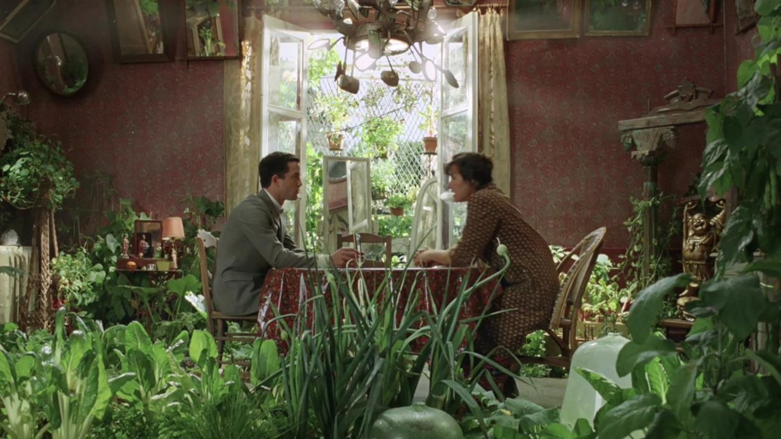 Un homme et une femme assis autour d'une table dans un appartement rempli de plantes vertes. Un homme et une femme assis autour d'une table dans un appartement rempli de plantes vertes.