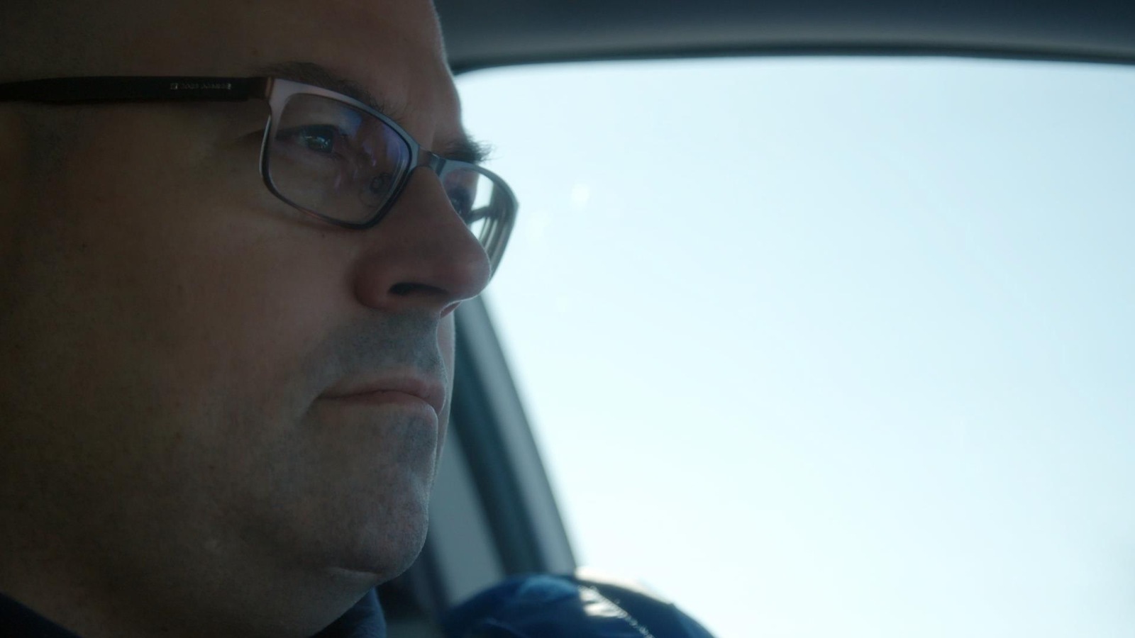Dans une voiture, le visage d'un homme qui porte des lunettes et qui regarde au loin. Dans une voiture, le visage d'un homme qui porte des lunettes et qui regarde au loin.