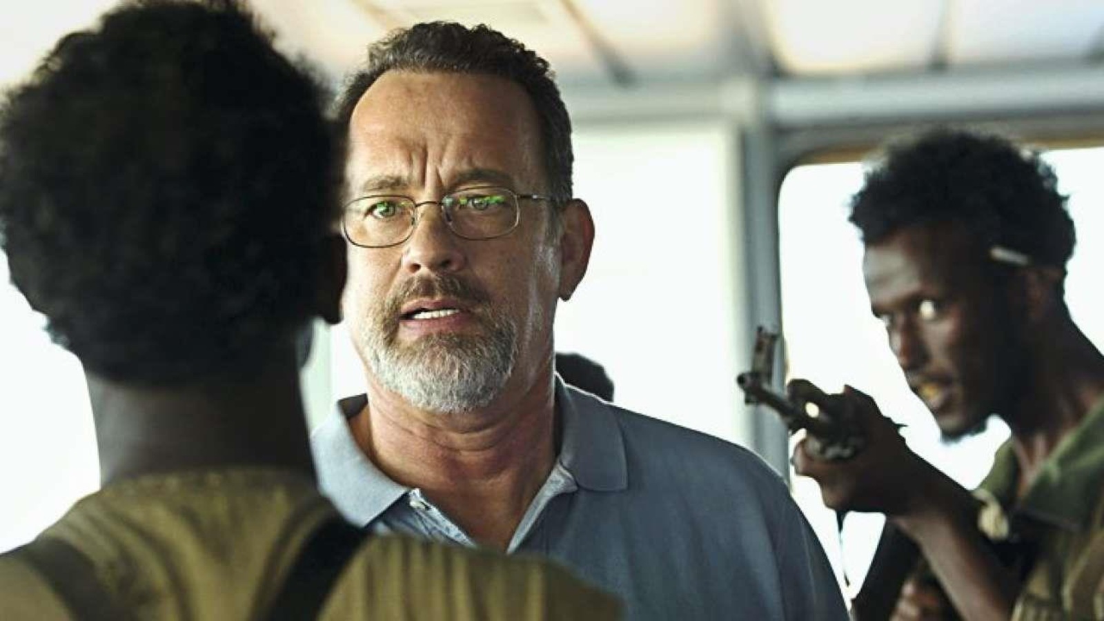 Un homme (Tom Hanks) tenu en joue par deux hommes armés. Un homme (Tom Hanks) tenu en joue par deux hommes armés.