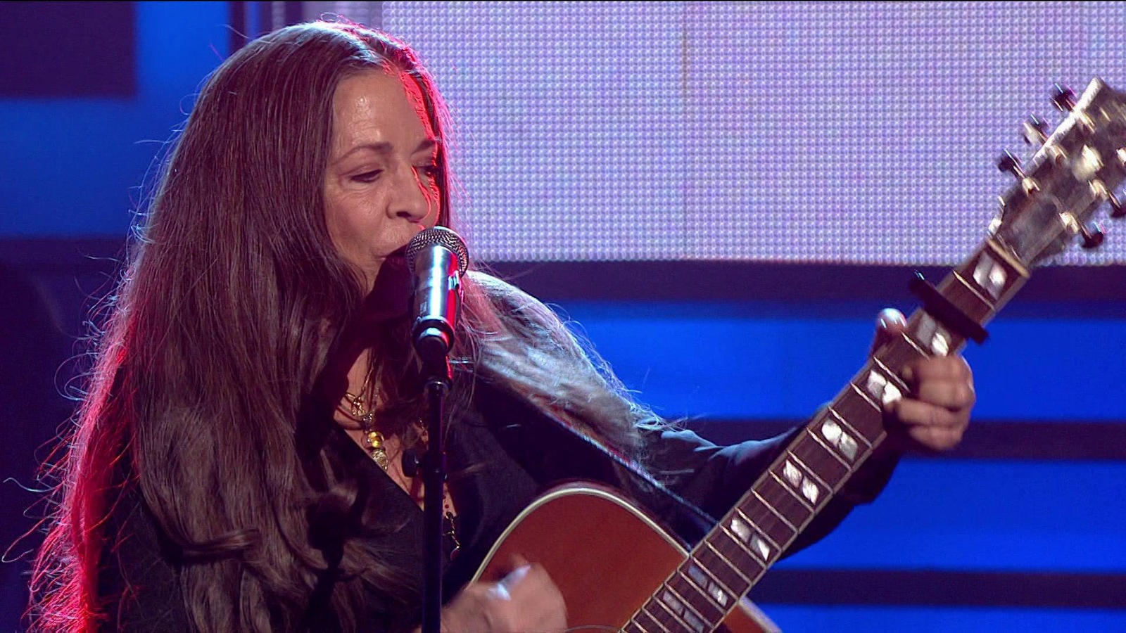 La chanteuse aux cheveux longs joue de la guitare et chante dans un micro. La chanteuse aux cheveux longs joue de la guitare et chante dans un micro.