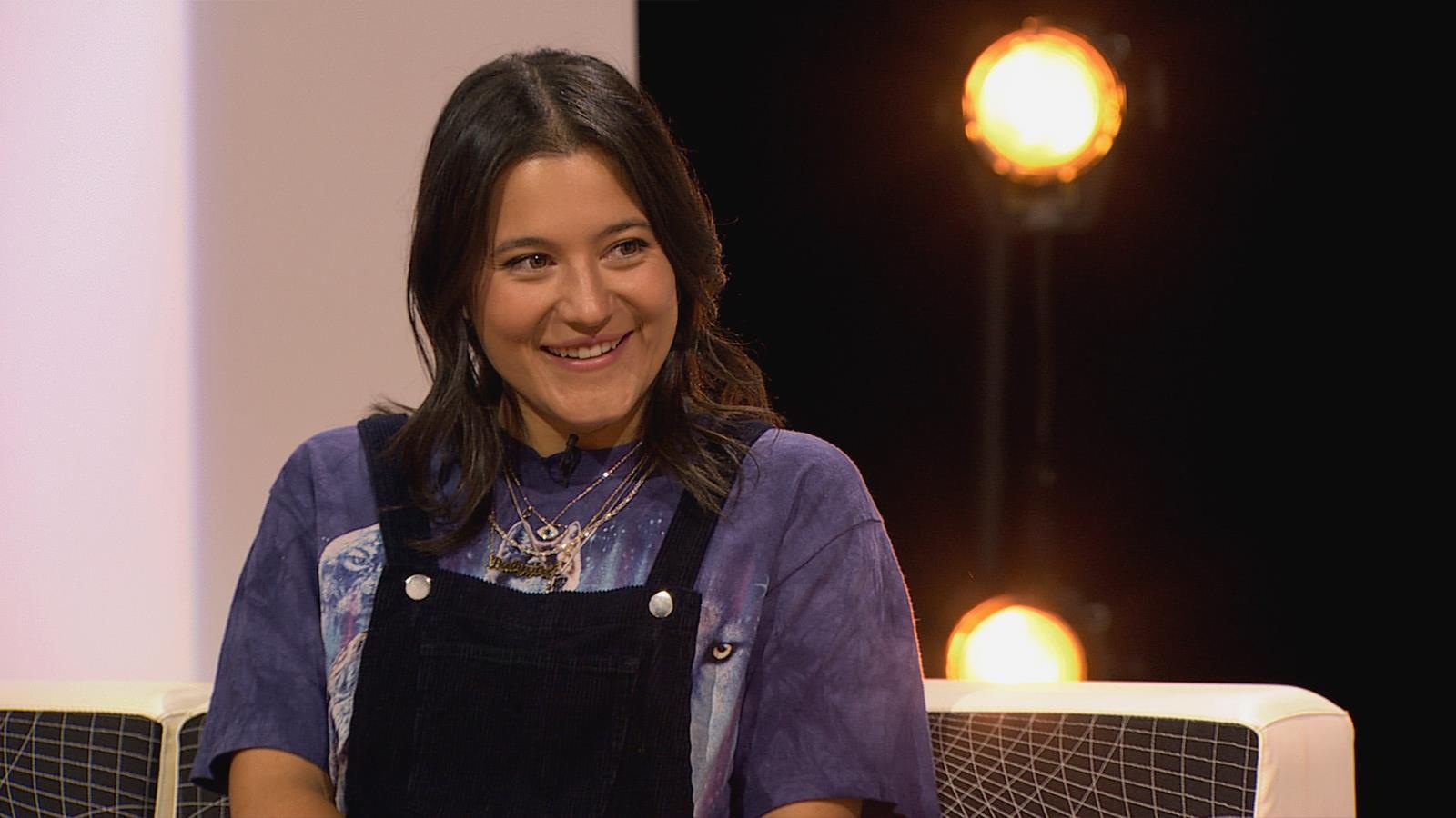 La jeune femme est assise dans un studio de télévision et sourit. La jeune femme est assise dans un studio de télévision et sourit.