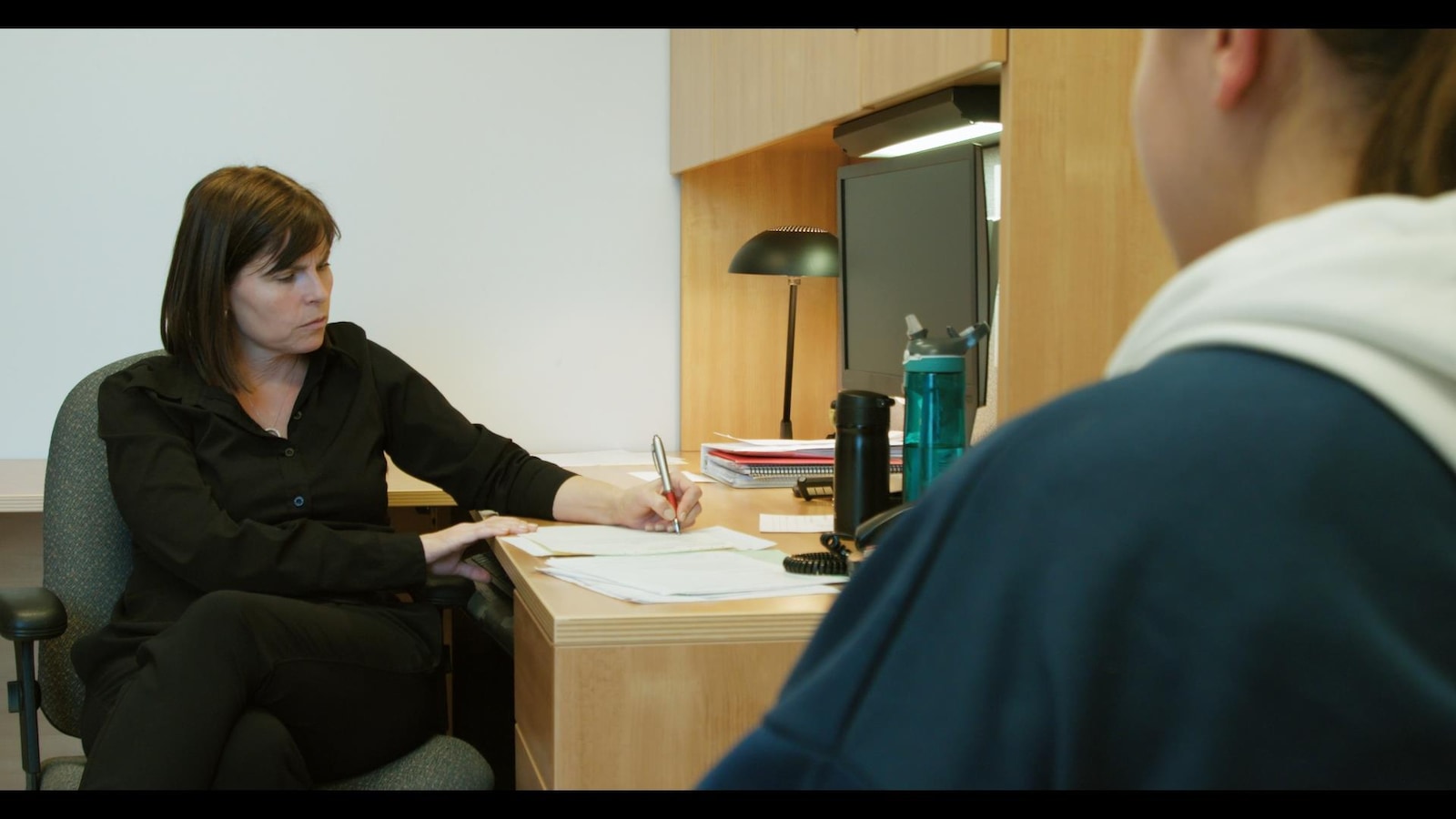 La femme est assise et écrit sur une feuille à son bureau. La femme est assise et écrit sur une feuille à son bureau.