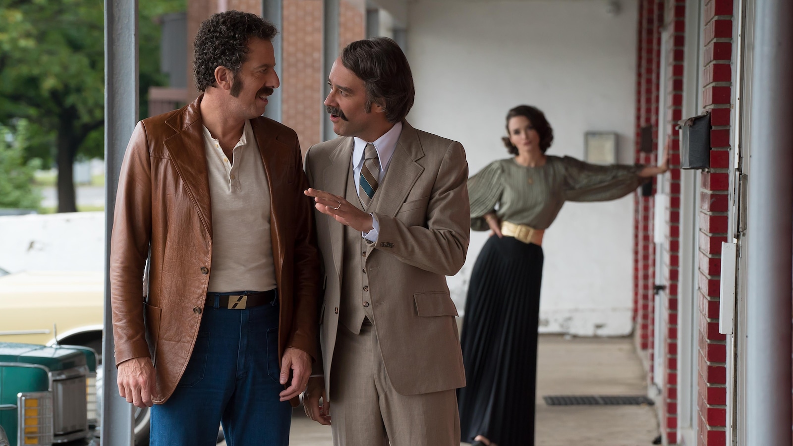 Deux hommes marchent la galerie d'un motel, tandis qu'une femme les regarde. Deux hommes marchent la galerie d'un motel, tandis qu'une femme les regarde.