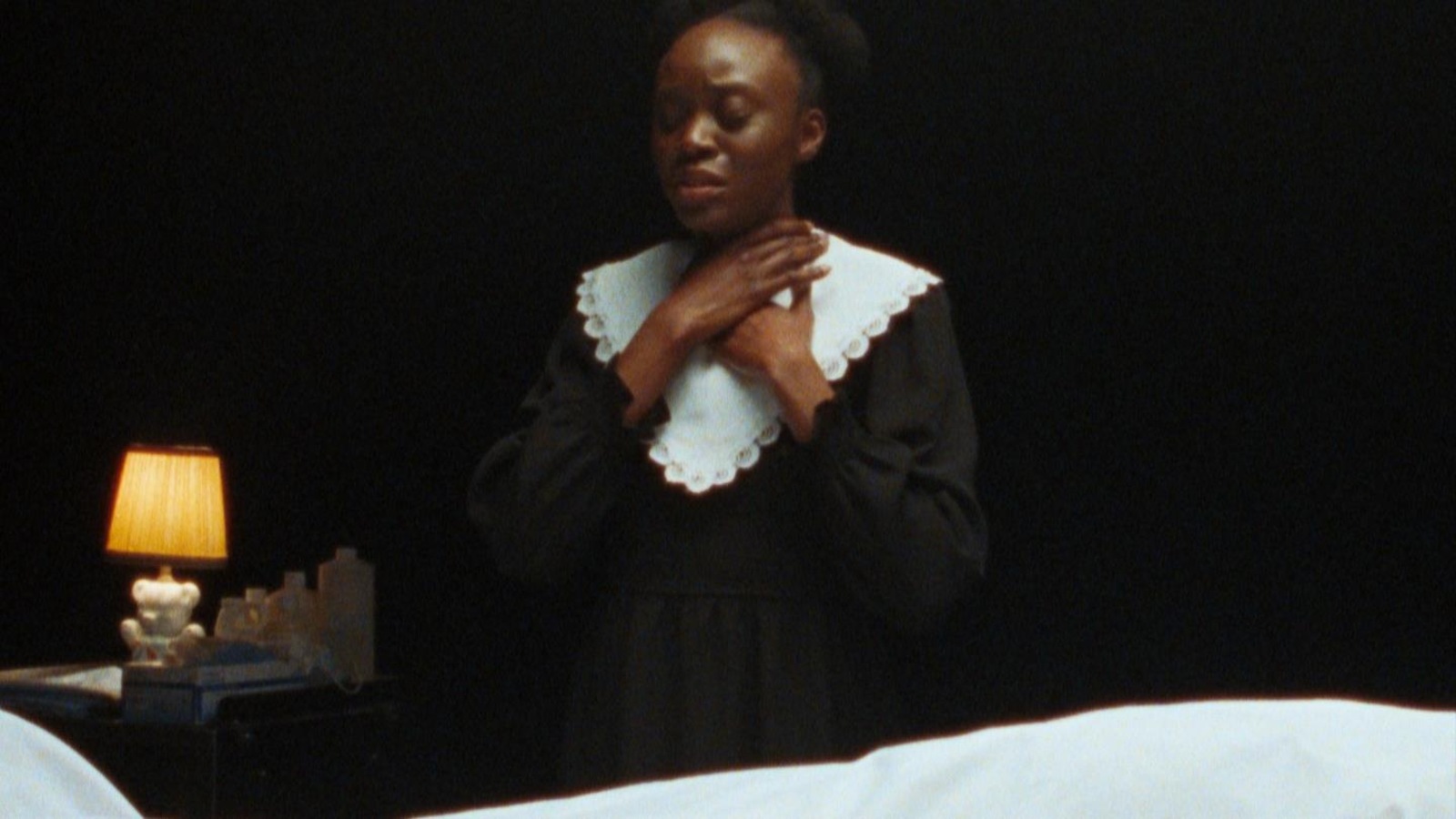 Une jeune femme (Schelby Jean-Baptiste) les mains sur le cou, les yeux fermés.