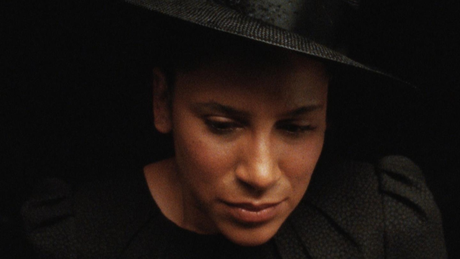 Une femme portant chapeau et habit noirs en gros plan.