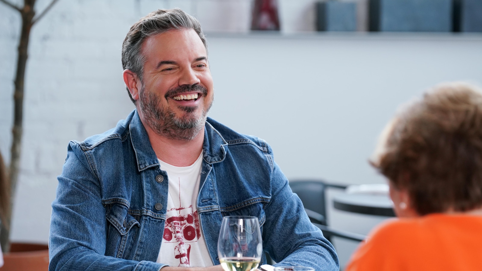 Charles Lafortune est assis à table. Il y a un verre de vin devant lui.