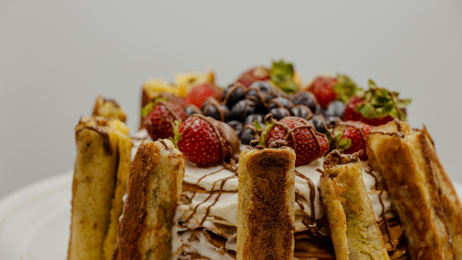 Gâteau blanc entouré de crêpes roulées et nappé de ftuits de saison et de coulis chocolat. Gâteau blanc entouré de crêpes roulées et nappé de ftuits de saison et de coulis chocolat.