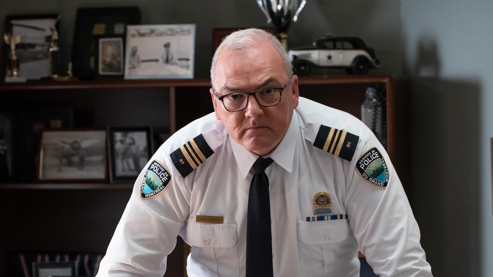 Un chef de police interprété par Gildor Roy est penché sur son bureau Un chef de police interprété par Gildor Roy est penché sur son bureau