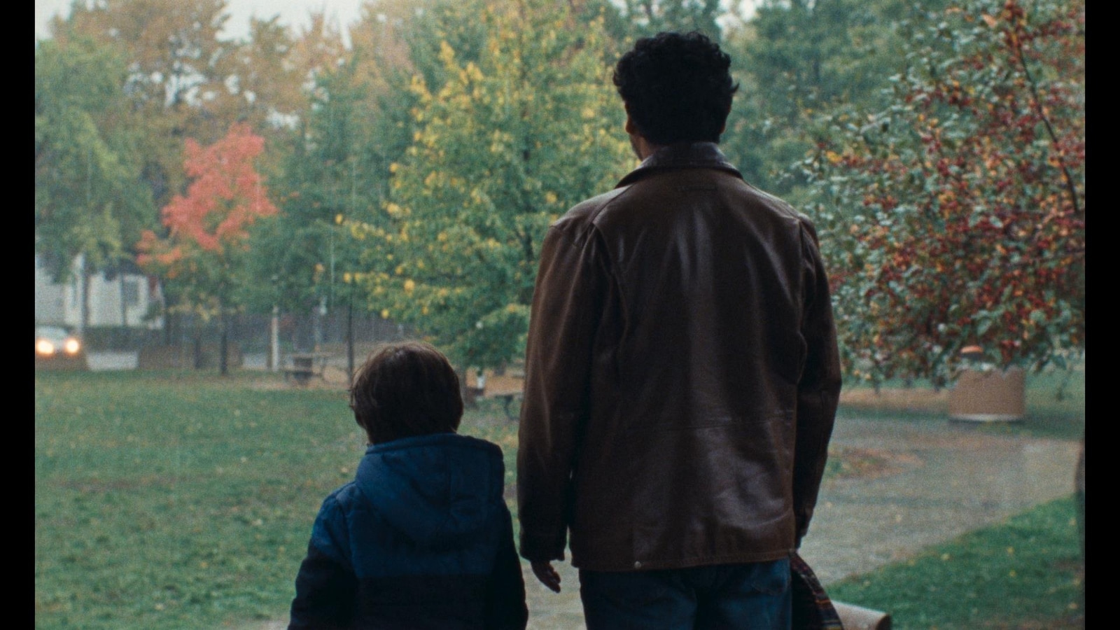 Un petit garçon et un homme, de dos, regardent un parc. Un petit garçon et un homme, de dos, regardent un parc.