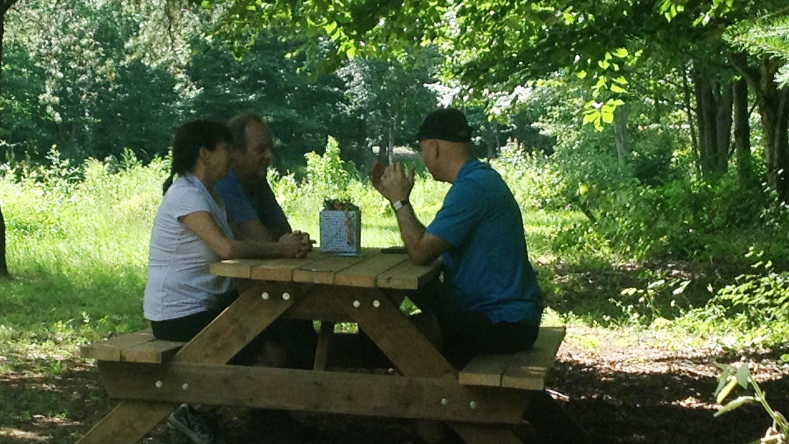 Trois personnes sont assises autour d'une table de pique-nique à l'extérieur. Trois personnes sont assises autour d'une table de pique-nique à l'extérieur.