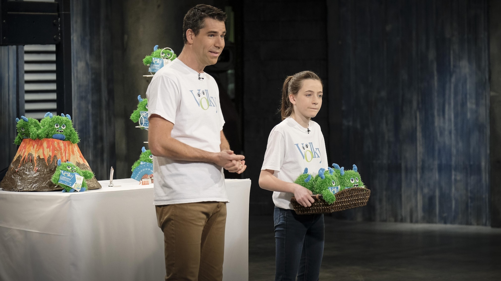 Il est accompagné d'une jeune fille qui tient dans ses mains un panier contenant des peluches vertes avec des cornes bleues. Il est accompagné d'une jeune fille qui tient dans ses mains un panier contenant des peluches vertes avec des cornes bleues.