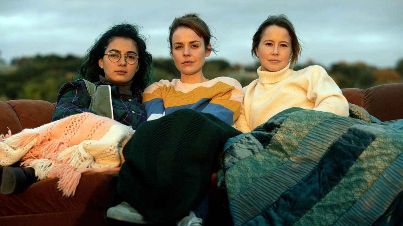 Trois jeunes filles (Mounia Zazham, Noémie O'Farrell, Juliette Gosselin) sur un divan, à l'extérieur, des couvertures sur les jambes. Trois jeunes filles (Mounia Zazham, Noémie O'Farrell, Juliette Gosselin) sur un divan, à l'extérieur, des couvertures sur les jambes.