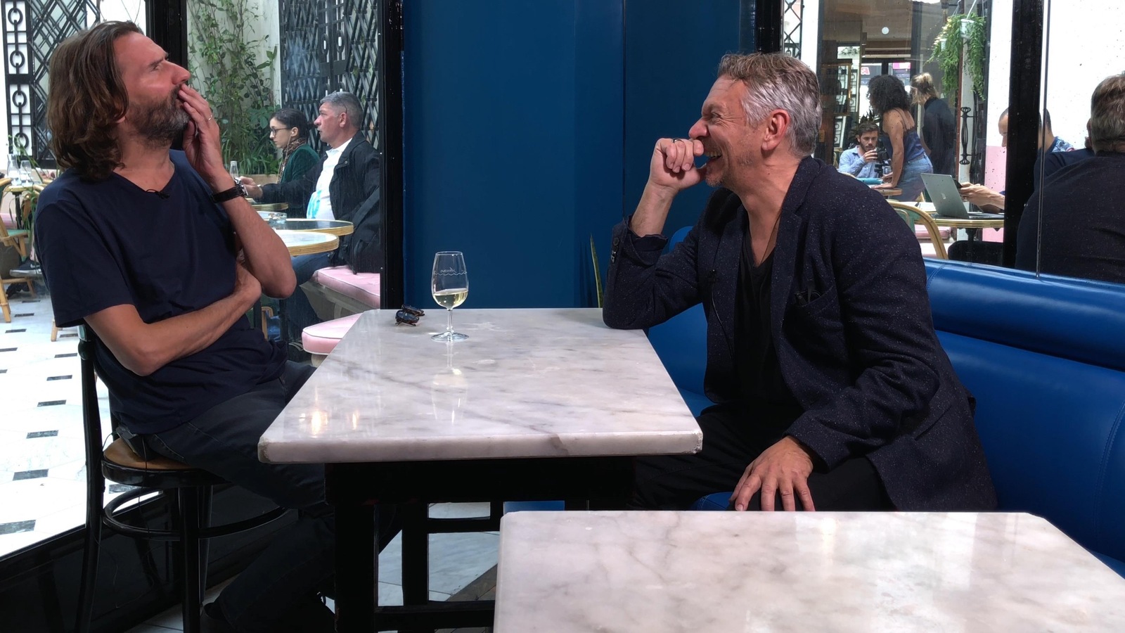 Ils sont assis à la table d'un restaurant. Marc est assis sur une banquette en cuir bleu et il rit. Ils sont assis à la table d'un restaurant. Marc est assis sur une banquette en cuir bleu et il rit.