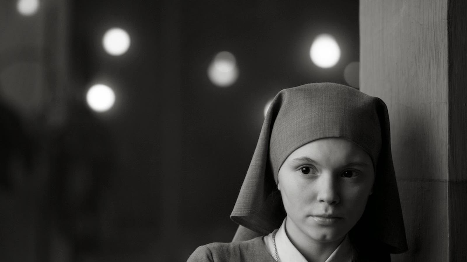 En noir et blanc, une jeune femme portant un habit de soeur, contre un pilier. En noir et blanc, une jeune femme portant un habit de soeur, contre un pilier.