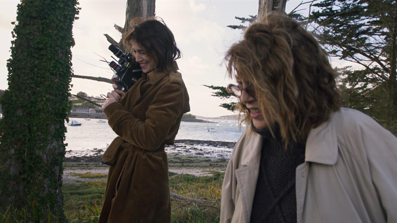 Dans une jardin, une femme qui tient une caméra (Charlotte Gainsbourg) et une femme (Jane Birkin) rient. Dans une jardin, une femme qui tient une caméra (Charlotte Gainsbourg) et une femme (Jane Birkin) rient.