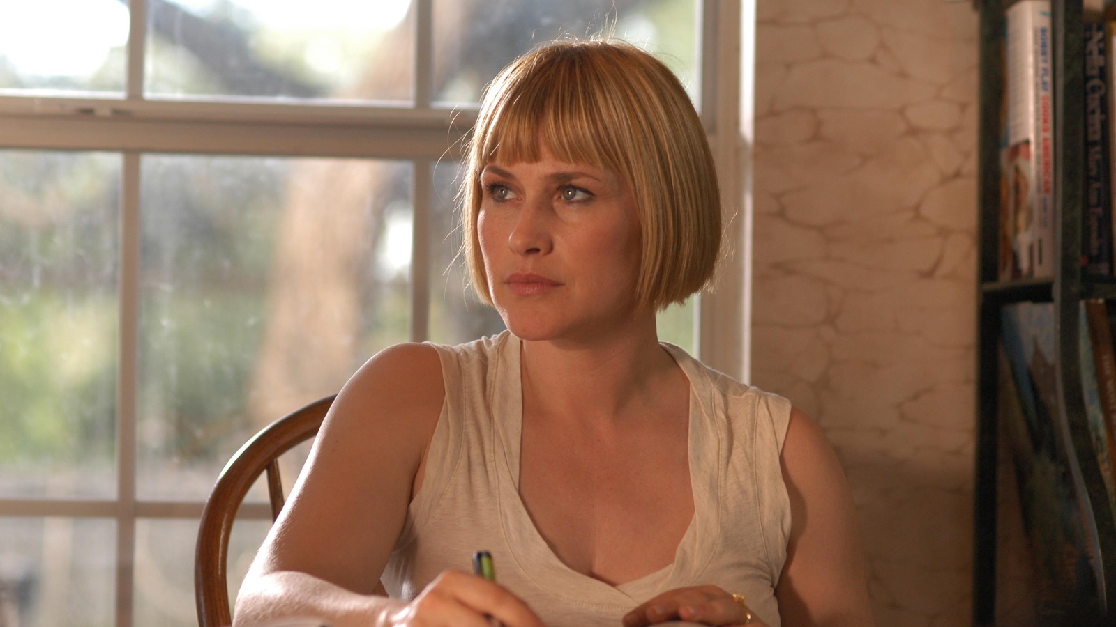 Une femme (Patricia Arquette) assise à une table, un stylo dans les mains et des livres devant elle. Une femme (Patricia Arquette) assise à une table, un stylo dans les mains et des livres devant elle.