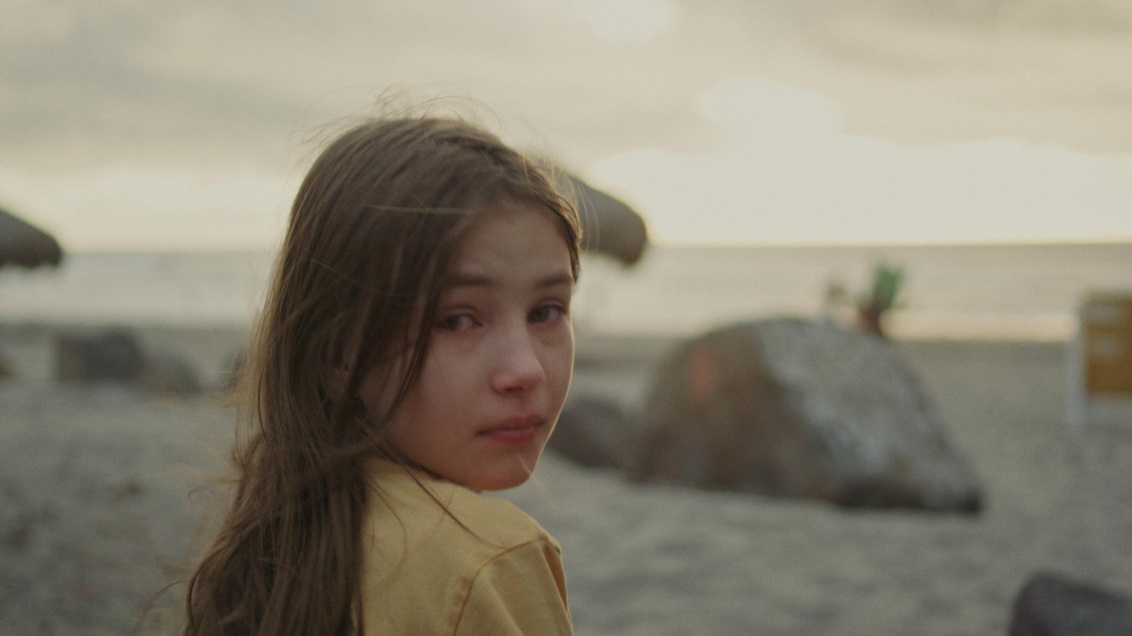 Une petite fille, sur la plage, regarde en arrière d'elle. Une petite fille, sur la plage, regarde en arrière d'elle.