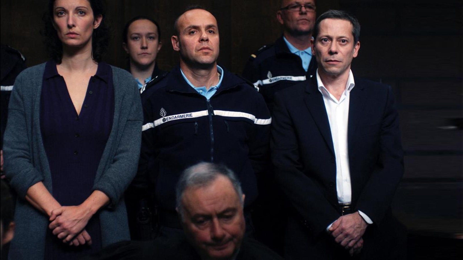 Un homme et une femme au tribunal, entourés de policiers Un homme et une femme au tribunal, entourés de policiers