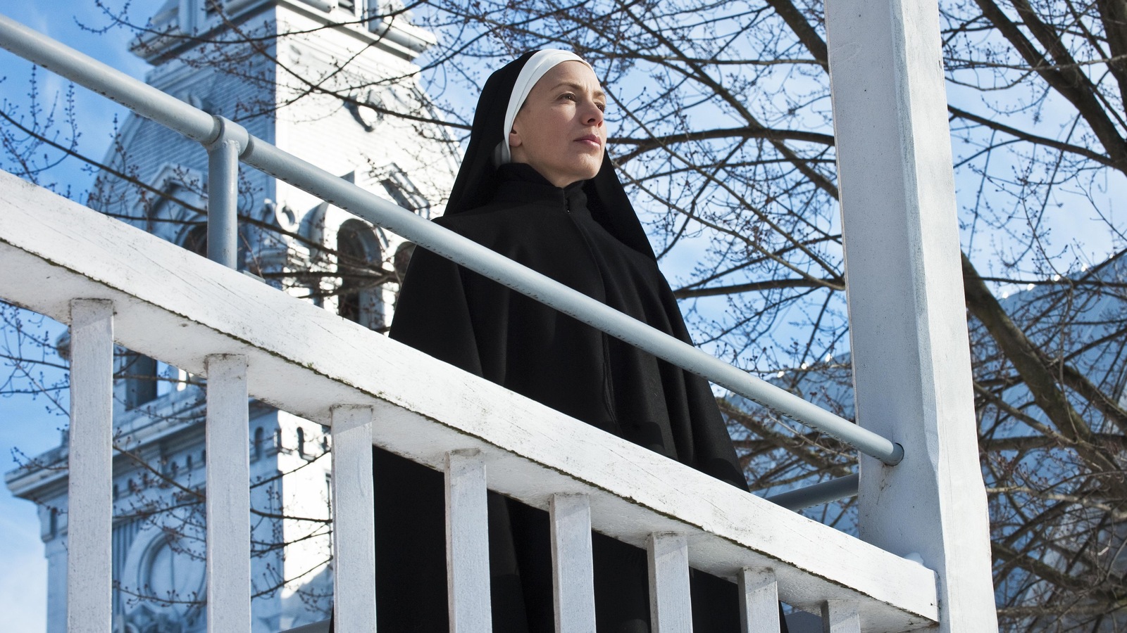 Une religieuse regarde au loin, sur un balcon.