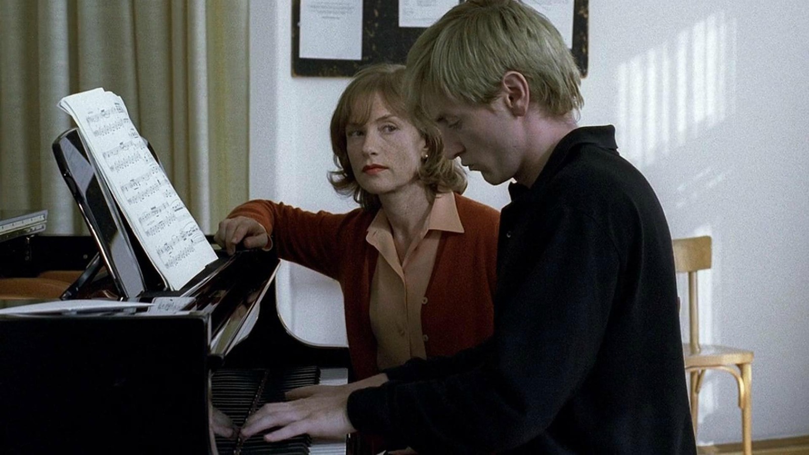 Une femme assise regarde son élève se pratiquer au piano. Une femme assise regarde son élève se pratiquer au piano.