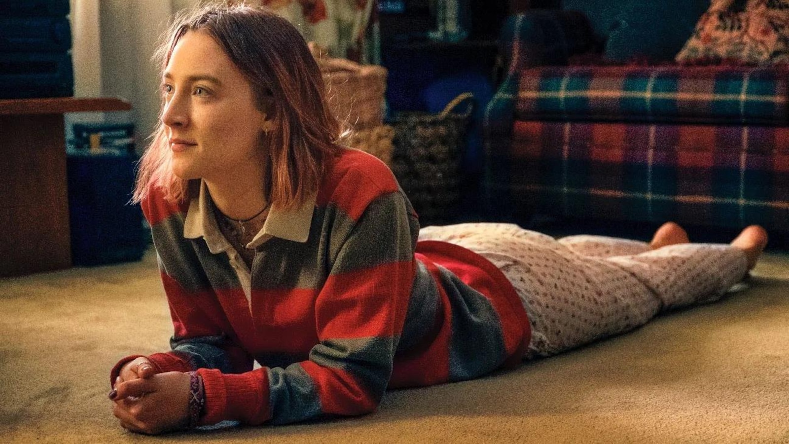 A young woman (Saoirse Ronan) is somewhere on her stomach, on the floor.