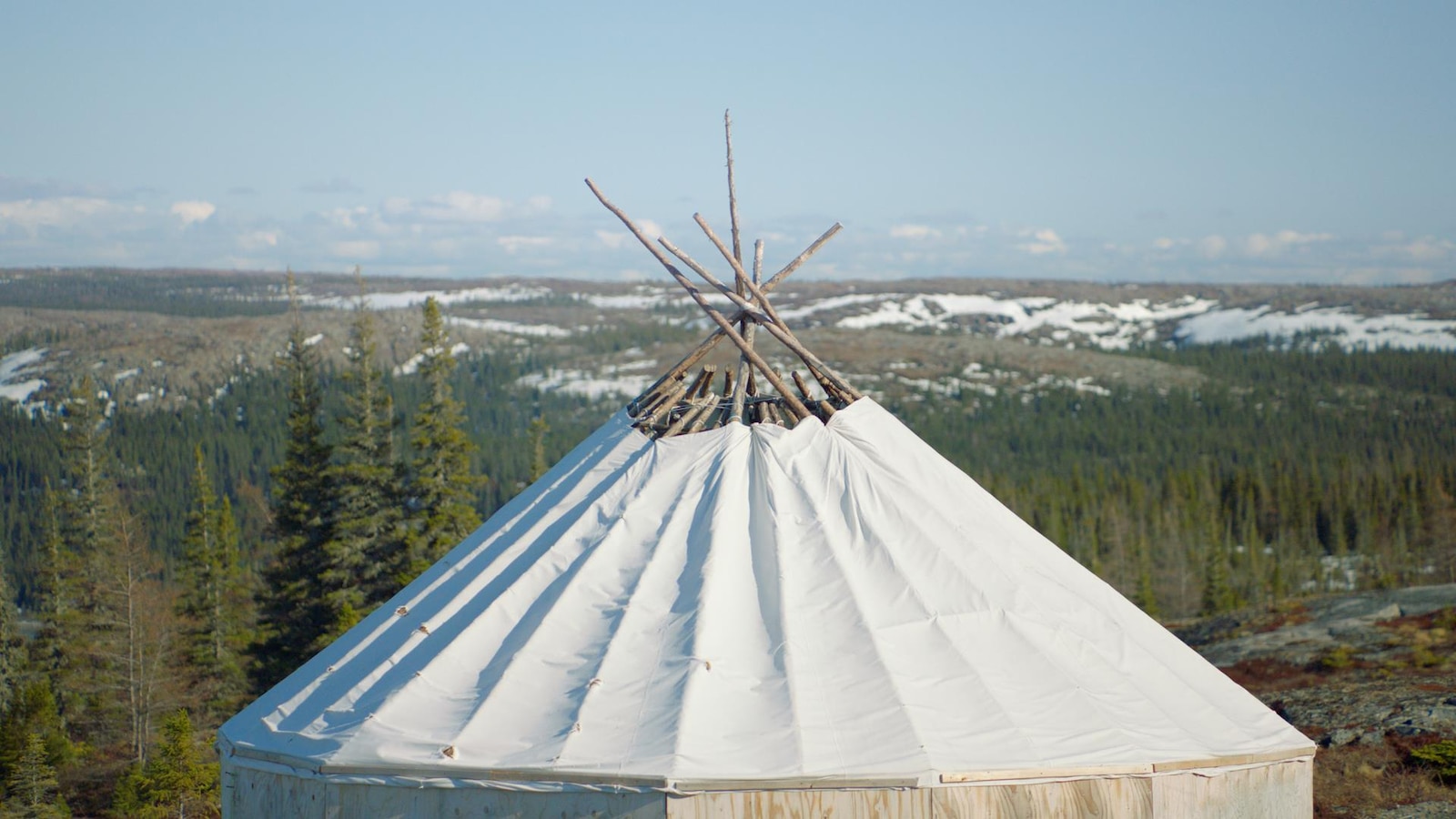 Un abri traditionnel trône dans un paysage de forêt de conifères.