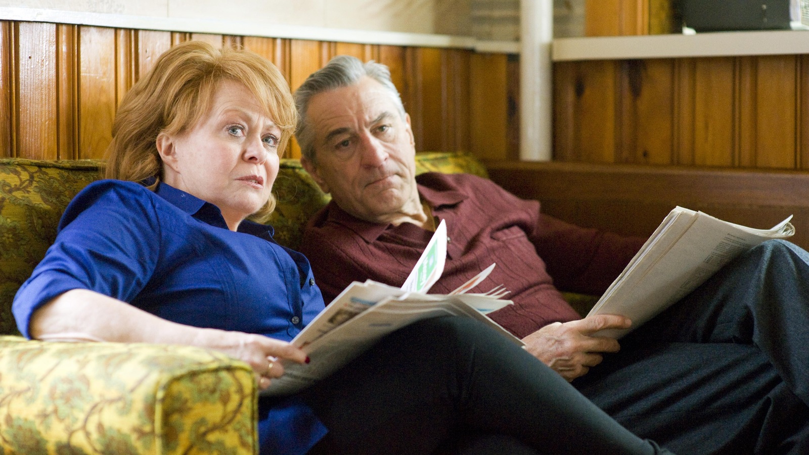 Une femme (Jacki Weaver) et un homme (Robert DeNiro), plus âgés, sur un canapé, des journaux dans les mains. Une femme (Jacki Weaver) et un homme (Robert DeNiro), plus âgés, sur un canapé, des journaux dans les mains.