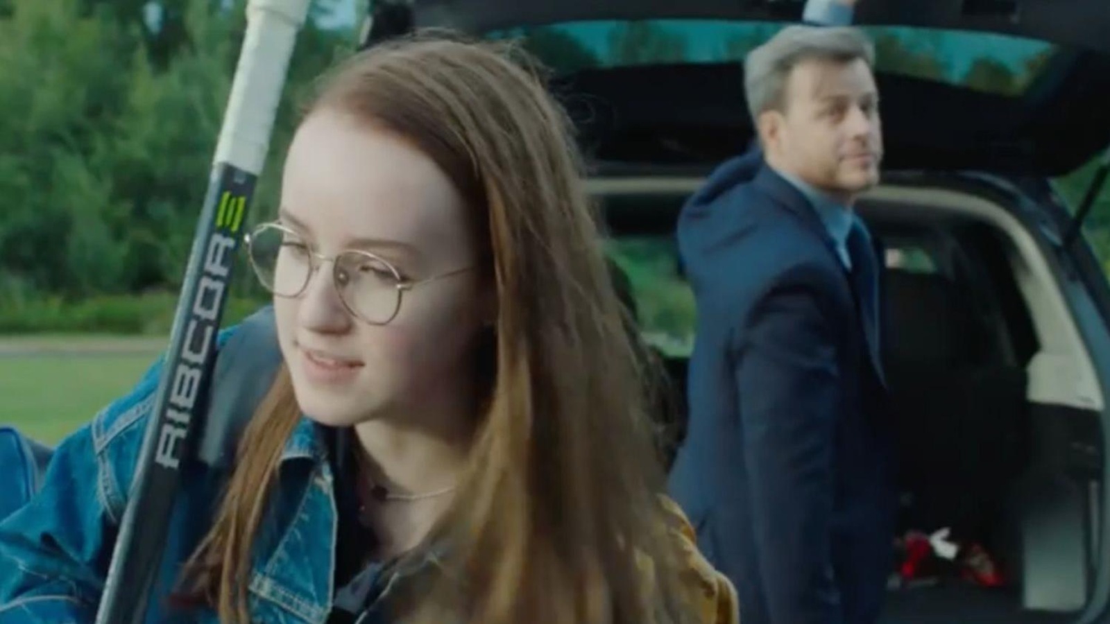 Un homme en costume (Louis Morissette) devant le coffre de sa voiture, regarde une jeune fille (Emilie Bierre) qui porte son équipement de hockey sur l'épaule. Un homme en costume (Louis Morissette) devant le coffre de sa voiture, regarde une jeune fille (Emilie Bierre) qui porte son équipement de hockey sur l'épaule.