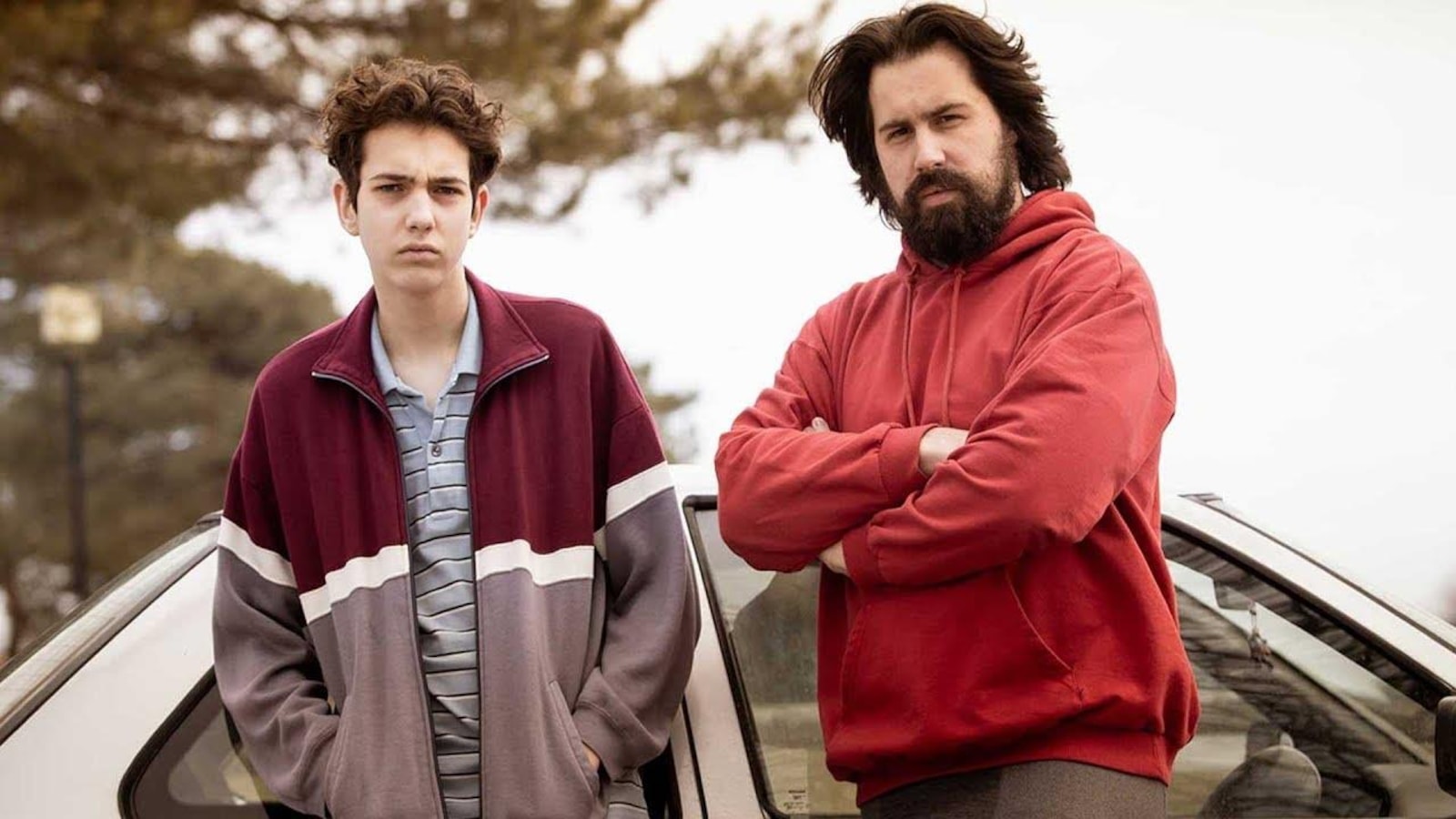 Un jeune homme (Justin Leyrolles-Bouchard) et un homme (Philippe-Audrey Larrue St-Jacques) fixent l'objectif, accotés sur une voiture. Un jeune homme (Justin Leyrolles-Bouchard) et un homme (Philippe-Audrey Larrue St-Jacques) fixent l'objectif, accotés sur une voiture.