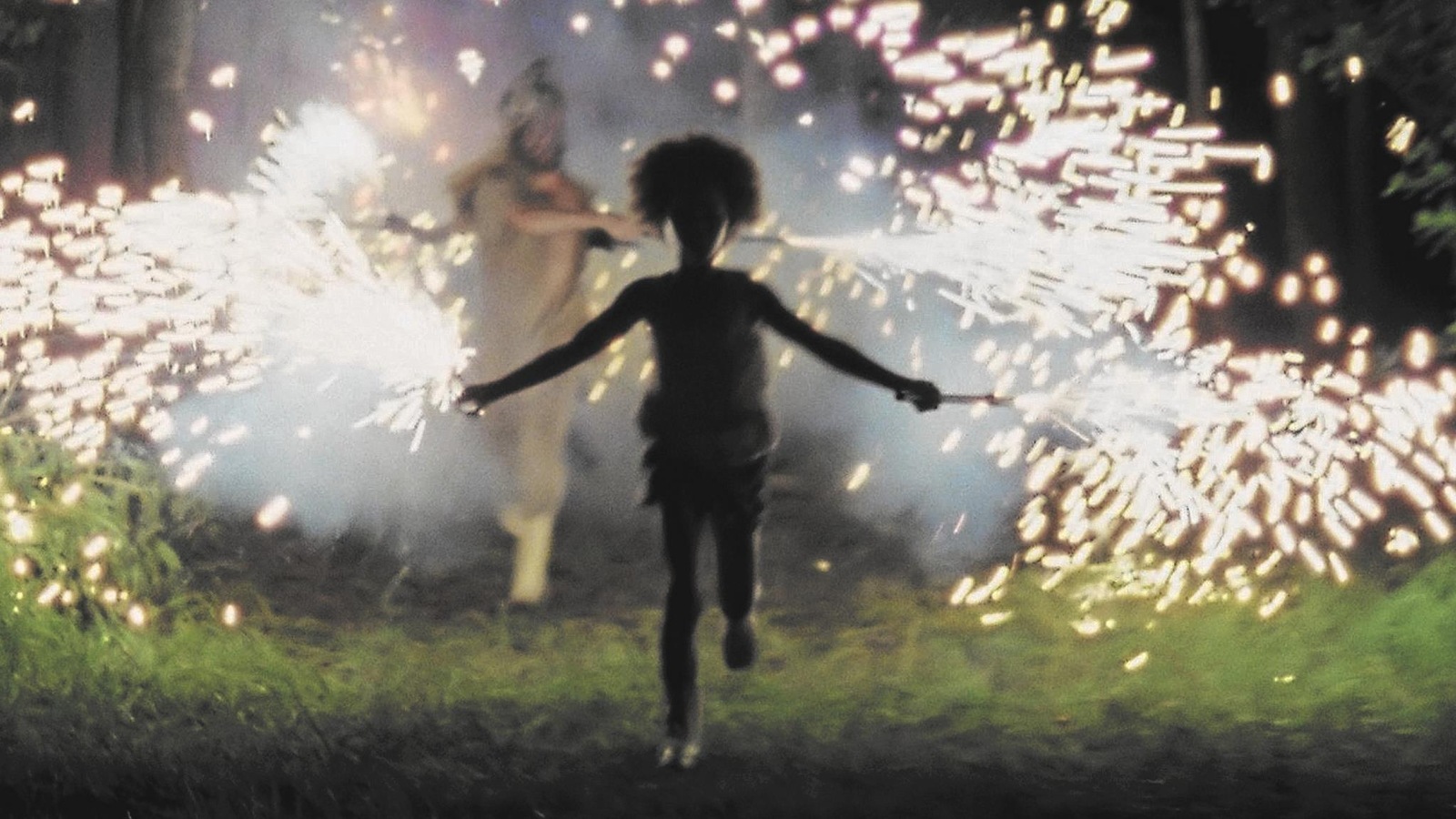 Une petite fille court dans la pénombre avec des feux d'artifice dans les mains. Une petite fille court dans la pénombre avec des feux d'artifice dans les mains.