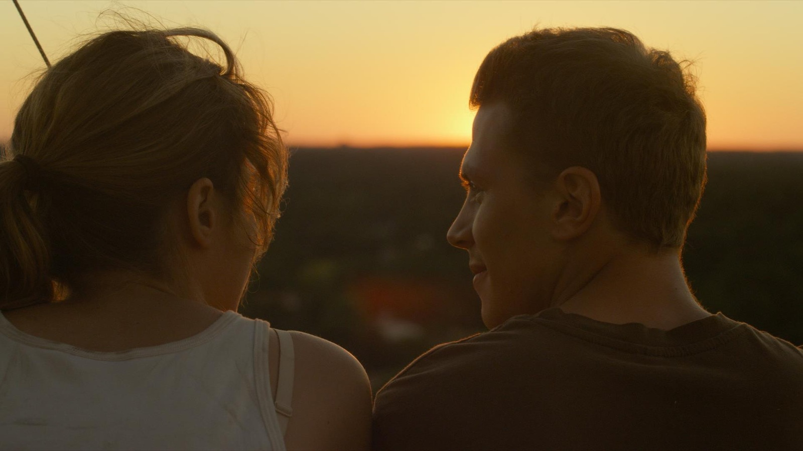 Une jeune femme et un jeune homme de dos, devant le soleil couchant. Une jeune femme et un jeune homme de dos, devant le soleil couchant.