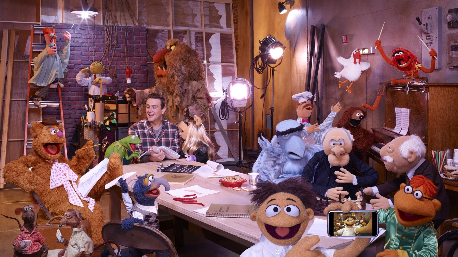 Les marionnettes des Muppets entourent Jason Segel sur un plateau de tournage encombré Les marionnettes des Muppets entourent Jason Segel sur un plateau de tournage encombré