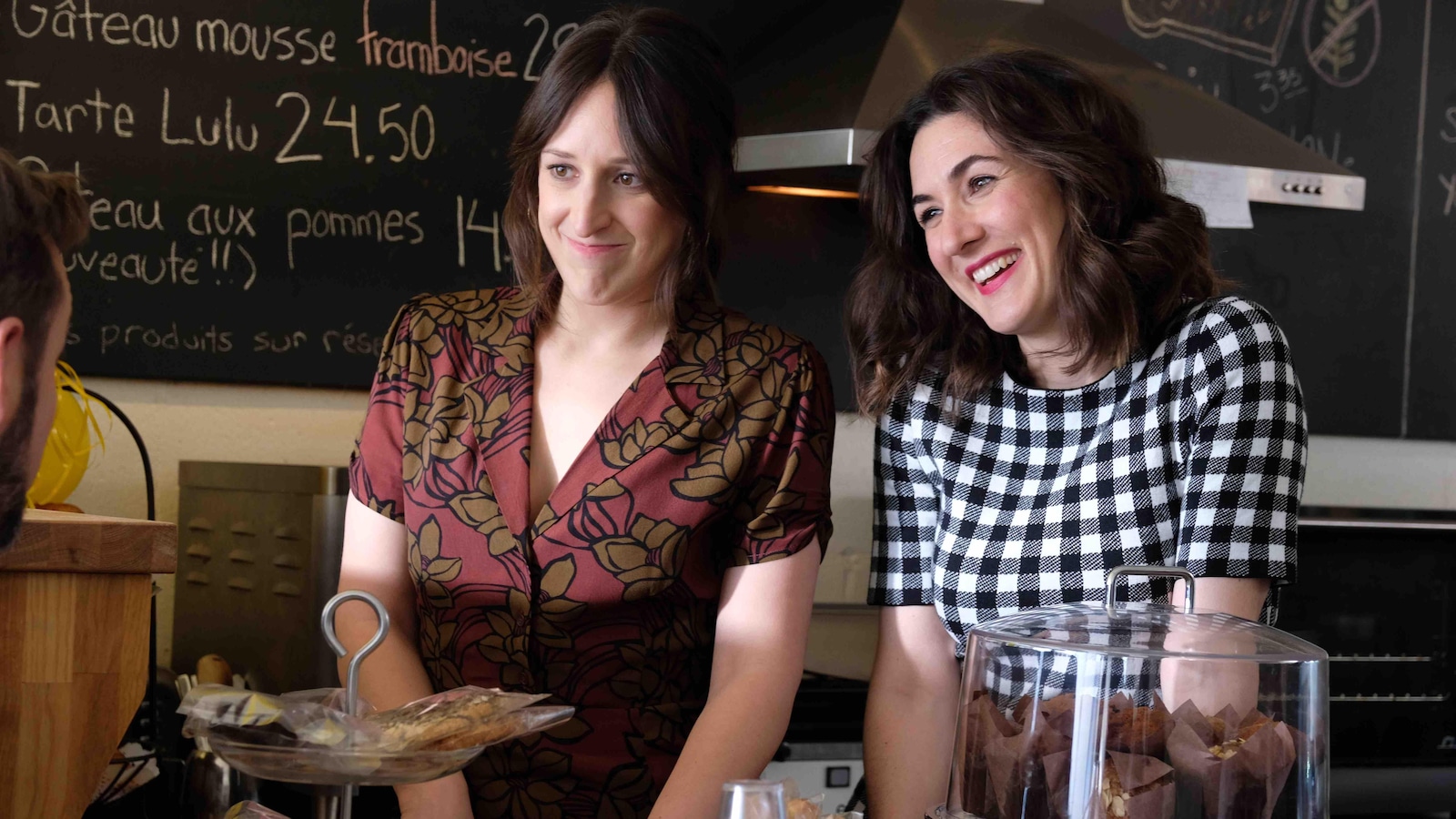 Maxim et Elizabeth sont derrière le comptoir d'un café qui contient des pâtisseries. Maxim et Elizabeth sont derrière le comptoir d'un café qui contient des pâtisseries.