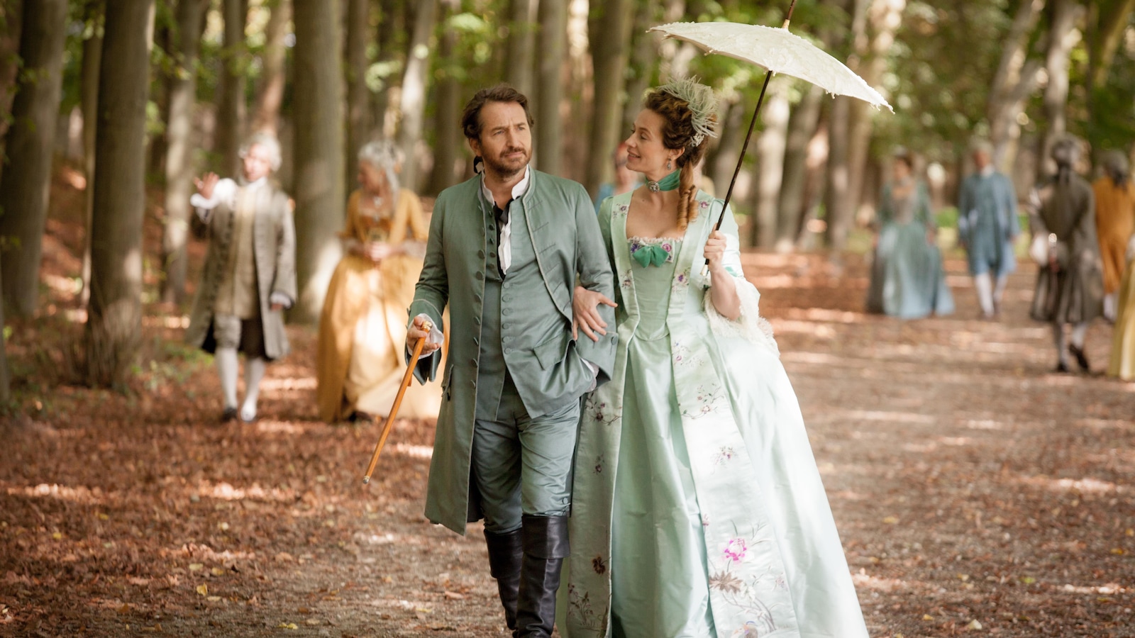 Un homme (Edouard Baer) et une femme (Cécile de France) en tenue d'époque se baladent dans un parc.