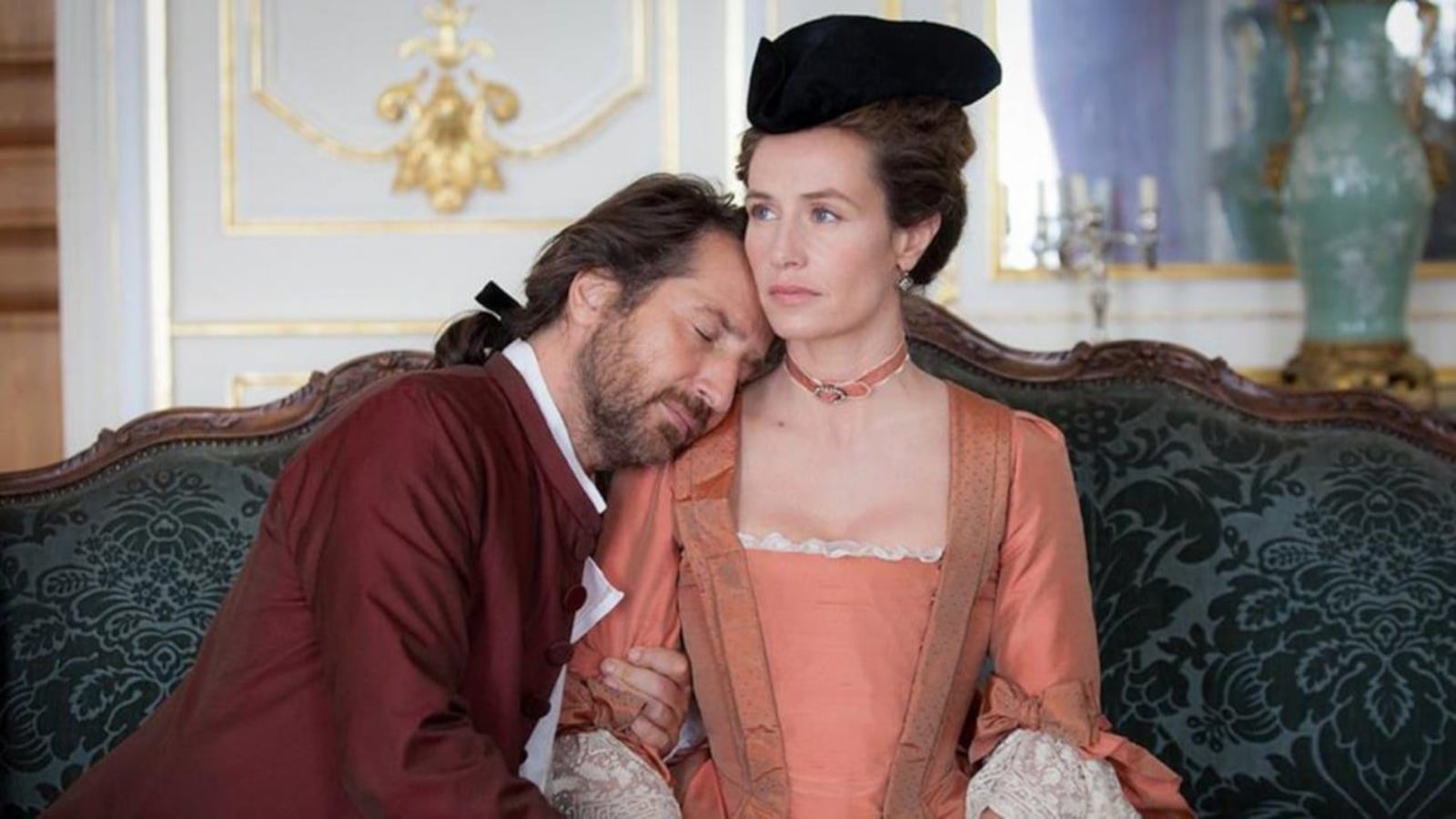 Un homme en tenue d'époque (Edouard Baer) la tête posée sur l'épaule d'une femme en robe d'époque (Cécile de France), sur un canapé.