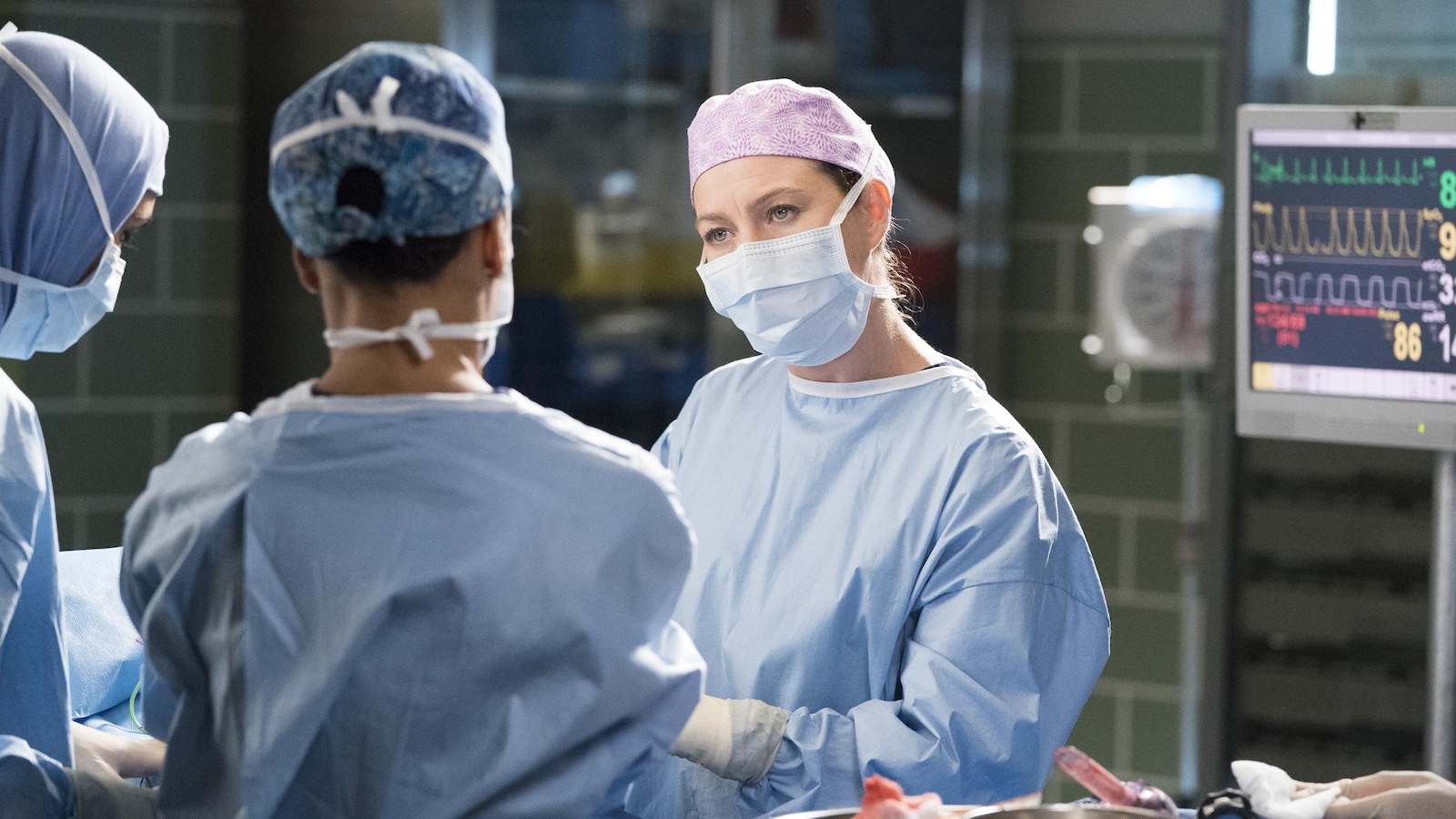 Trois médecins autour d'une table d'opération. Elles portent la blouse et le masque requis pour leur travail.