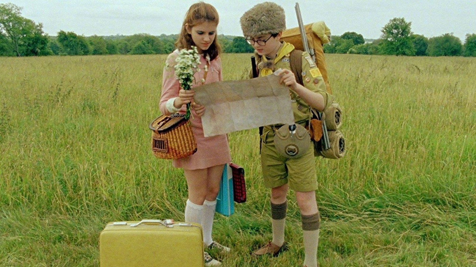 Une petite fille et un petit garçon habillé en scout regardent une carte dans une prairie. Une petite fille et un petit garçon habillé en scout regardent une carte dans une prairie.