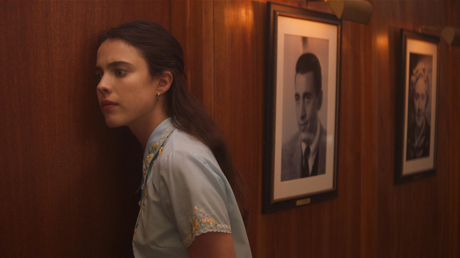 Une jeune femme (Margaret Qualley) écoute à la porte en bois d'un bureau. Une jeune femme (Margaret Qualley) écoute à la porte en bois d'un bureau.