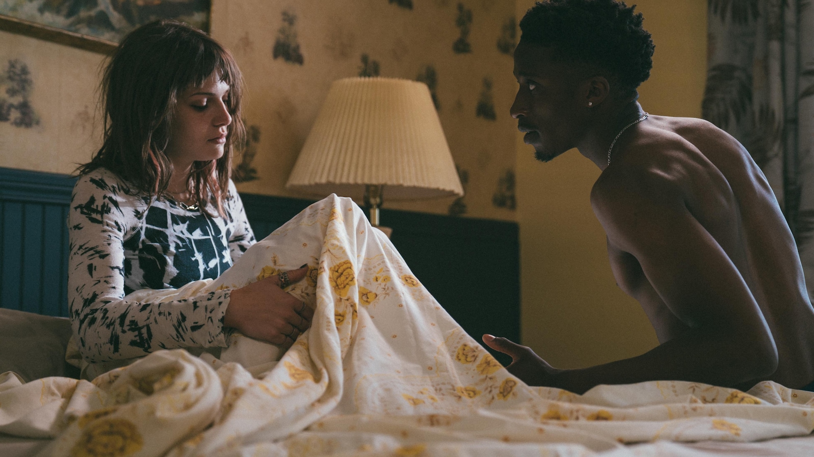 Une jeune femme (Kelly Depeault) et un jeune homme assis dans un lit.