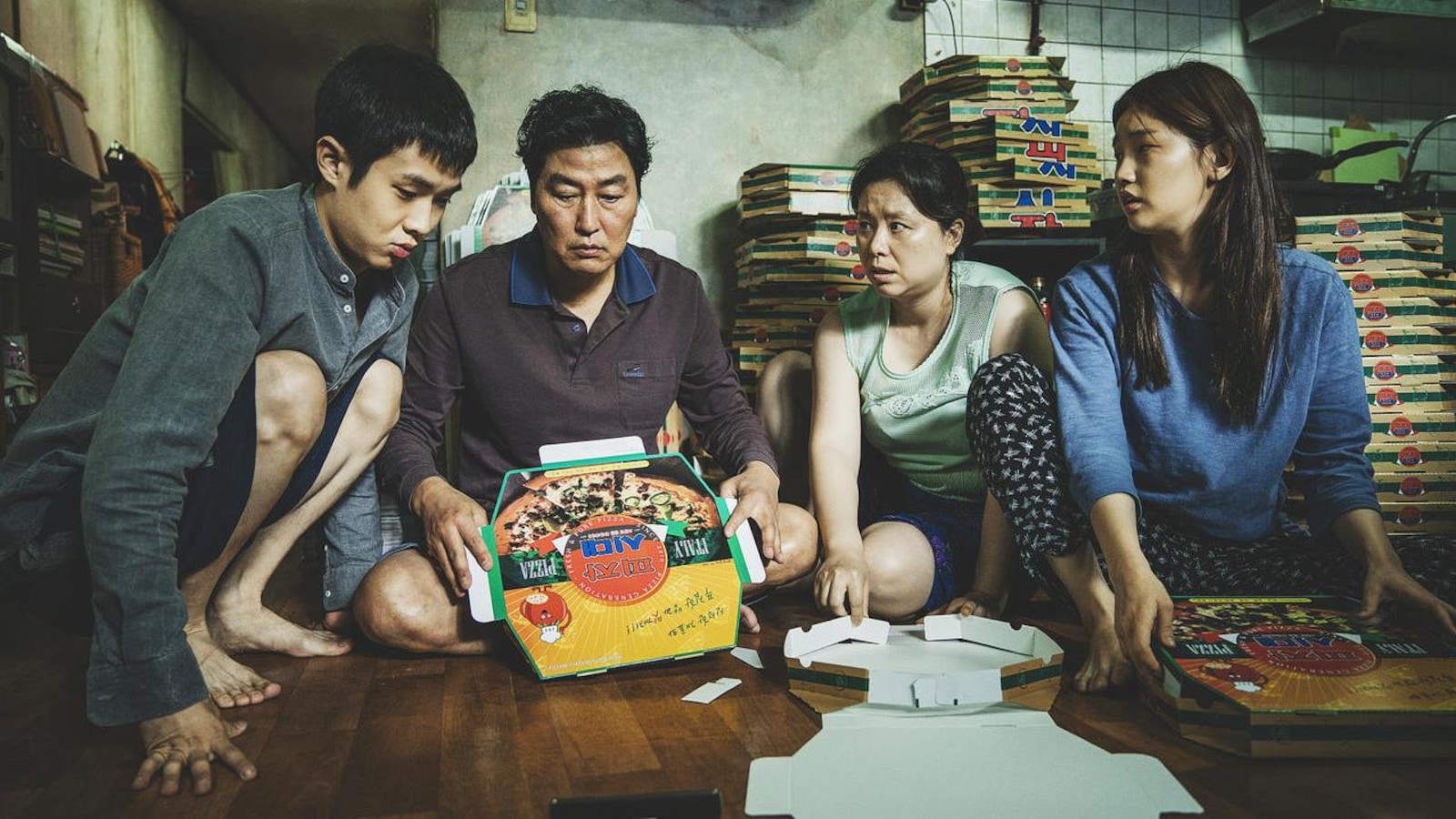 Une famille de quatre assise par terre, autour d'un carton de pizza. Une famille de quatre assise par terre, autour d'un carton de pizza.